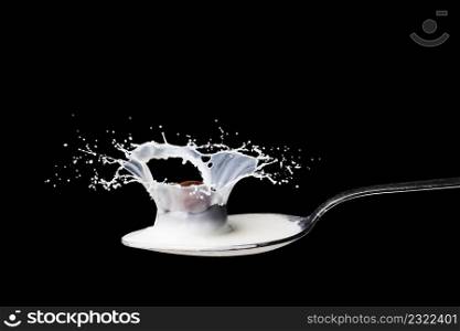 Spoon full of milk splashing on black background