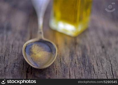 Spoon full of olive oil on wooden table
