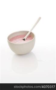 Spoon in bowl of pink porridge
