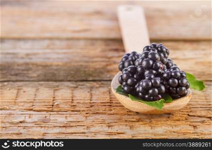 spoon of blackberries on wooden background closeup shot