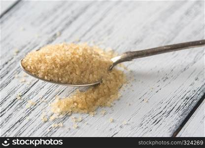 Spoon of brown sugar on the wooden background
