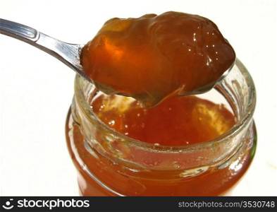 spoon scooping honey from jar on white background