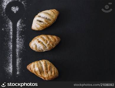 spoon shape made with flour near croissants black backdrop