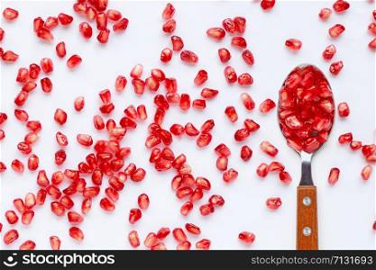 Spoon with pomegranate seeds isolated on white background.