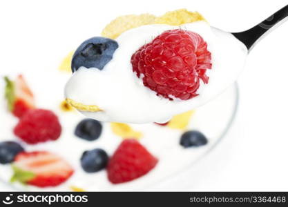 spoon with yogurt blueberry and a raspberry . spoon with yogurt blueberry and a raspberry and cornflakes over a dessert on white background