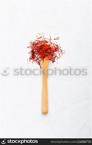 Spoonful of saffron on white wooden table top view flat lay.