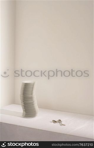 Spoons next to stack of plates on table. Simple