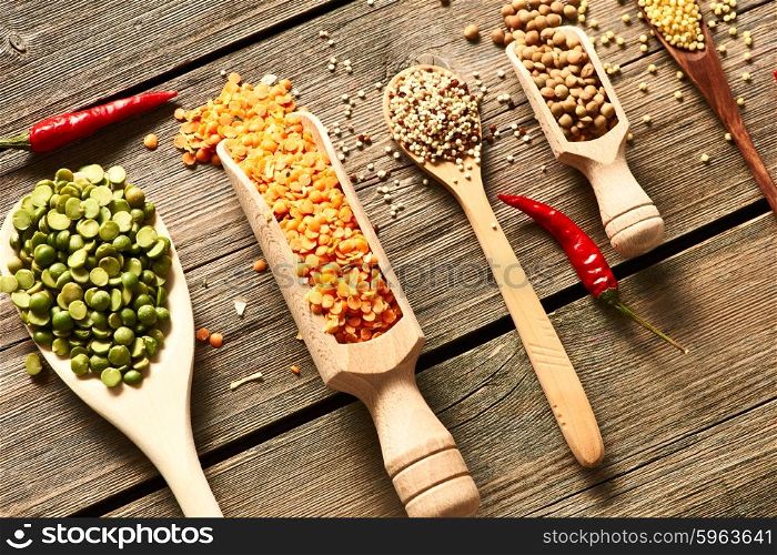 Spoons of various legumes on wooden background