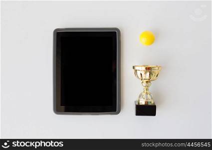 sport, achievement, championship, success and technology concept - close up of golf ball with golden cup and tablet pc computer with black blank screen over white background from top