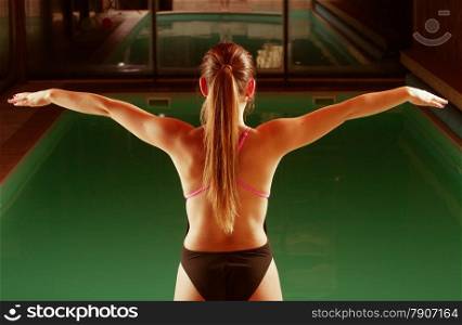Sport active lifestyle. Sporty woman female swimmer muscular fit body preparing to jumping and diving into swimming pool back view