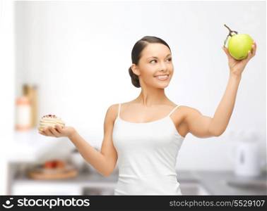 sport and diet concept - sporty woman with apple and cake in kitchen