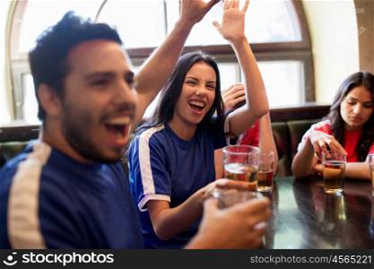 sport and entertainment concept - happy football fans or friends drinking beer, making high five and celebrating victory at bar or pub, supporting two teams with different shirt color