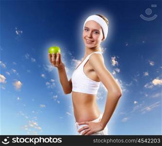Sport and healthy food. Young pretty girl in sport wear with green apple