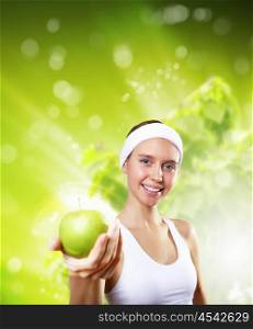 Sport and healthy food. Young pretty girl in sport wear with green apple