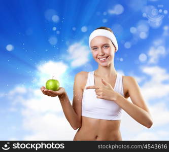 Sport and healthy food. Young pretty girl in sport wear with green apple