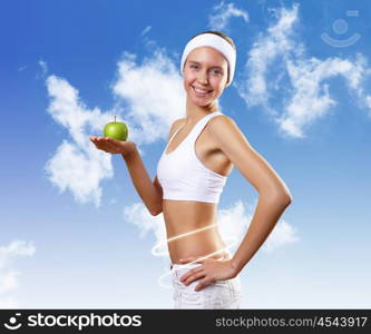 Sport and healthy food. Young pretty girl in sport wear with green apple