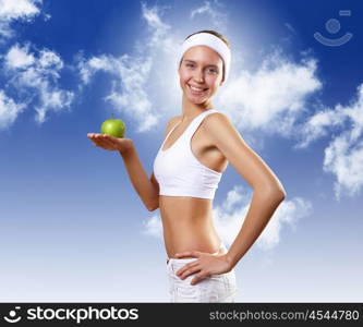 Sport and healthy food. Young pretty girl in sport wear with green apple