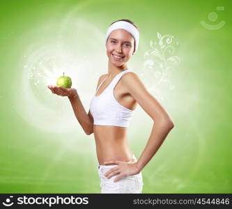 Sport and healthy food. Young pretty girl in sport wear with green apple