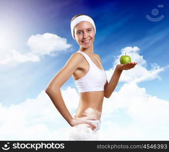 Sport and healthy food. Young pretty girl in sport wear with green apple