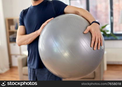 sport and healthy lifestyle concept - close up of man with fitness ball at home. close up of man with fitness ball at home