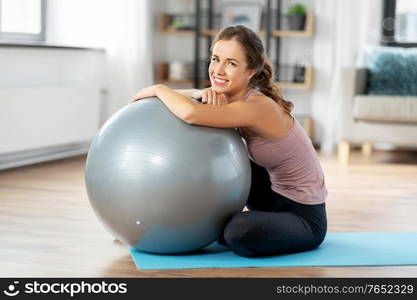 sport and healthy lifestyle concept - happy smiling young woman with fitness ball at home. happy young woman with fitness ball at home