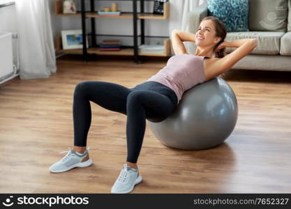 sport and healthy lifestyle concept - happy woman exercising on fitness ball at home. happy woman exercising on fitness ball at home