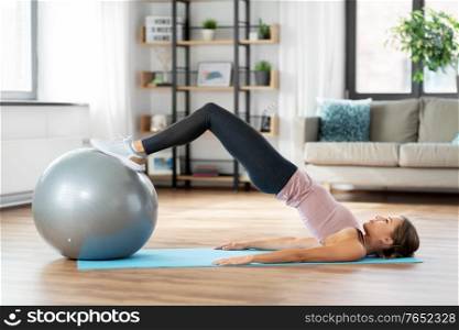 sport and healthy lifestyle concept - happy woman exercising on fitness ball at home. happy woman exercising on fitness ball at home