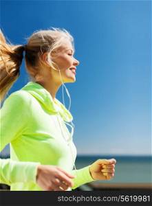 sport and lifestyle concept - woman doing running with earphones outdoors