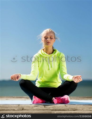 sport and lifestyle concept - woman doing yoga outdoors