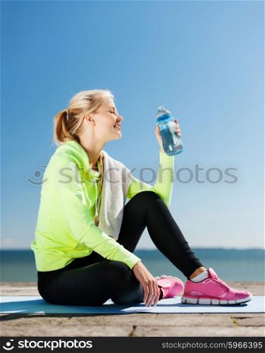 sport and lifestyle concept - woman drinking water after doing sports outdoors. woman drinking water after doing sports outdoors