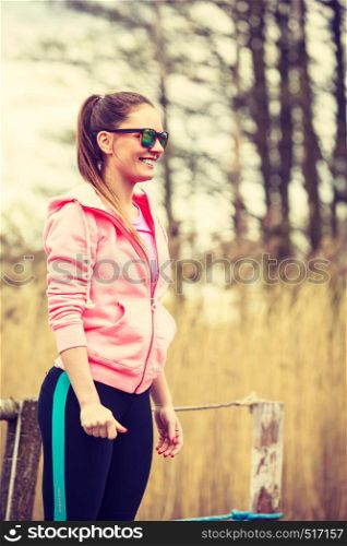 Sport and lifestyle concept. Young sports woman female jogger taking a break from running workout, relaxing on pier on sunny day. Young sports woman taking break after a run.