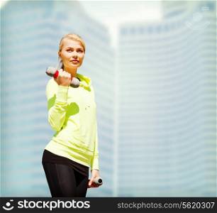 sport and lifestyle - young sporty woman with light dumbbells outdoors