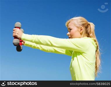 sport and lifestyle - young sporty woman with light dumbbells outdoors. sporty woman with light dumbbells outdoors