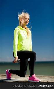 sport and lifestyle - young sporty woman with light dumbbells outdoors. sporty woman with light dumbbells outdoors