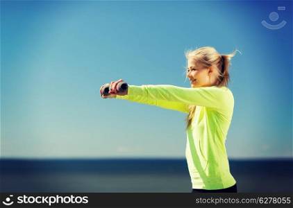 sport and lifestyle - young sporty woman with light dumbbells outdoors