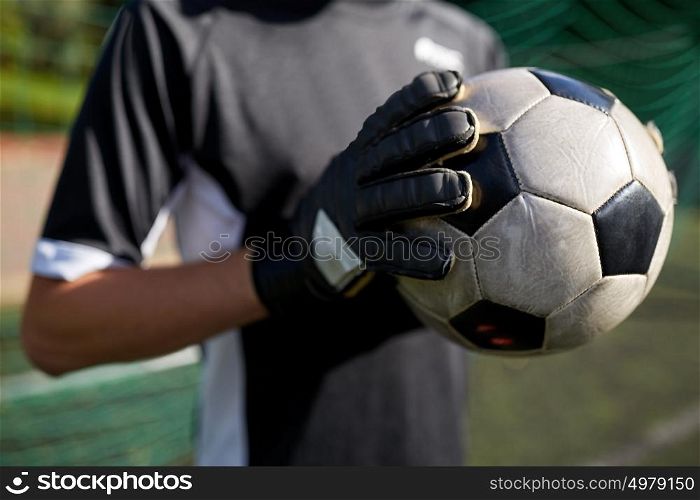 sport and people - close up of soccer player or goalkeeper holding ball at football goal on field. close up of goalkeeper with ball playing football