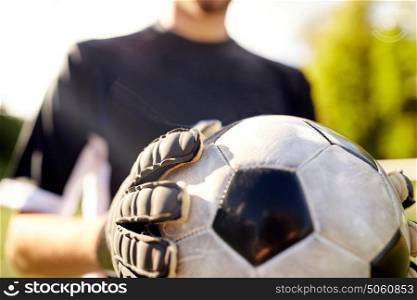 sport and people - close up of soccer player or goalkeeper holding ball at football goal on field. close up of goalkeeper with ball playing football