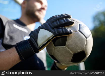 sport and people - close up of soccer player or goalkeeper holding ball at football goal on field. close up of goalkeeper with ball playing football