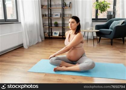 sport and people concept - happy pregnant woman doing yoga at home. happy pregnant woman doing yoga at home