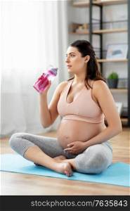 sport and people concept - happy pregnant woman drinking water after yoga at home. pregnant woman drinking water after yoga at home
