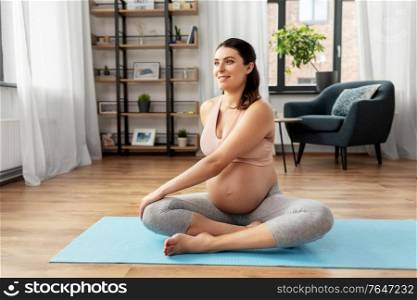 sport and people concept - happy smiling pregnant woman doing yoga at home. happy pregnant woman doing yoga at home