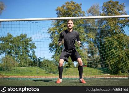 sport and people - soccer player or goalkeeper at football goal on field. goalkeeper or soccer player at football goal