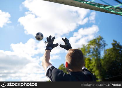 sport and people - soccer player or goalkeeper catching ball at football goal on field. goalkeeper with ball at football goal on field