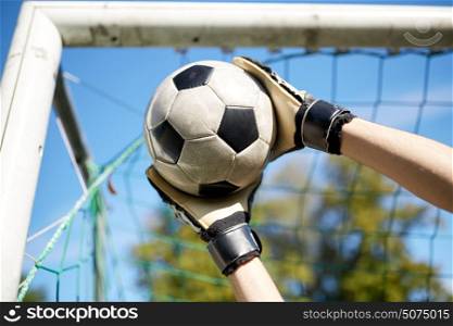 sport and people - soccer player or goalkeeper catching ball at football goal on field. goalkeeper with ball at football goal on field