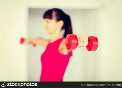 sport and recreation concept - sporty woman hands with light red dumbbells
