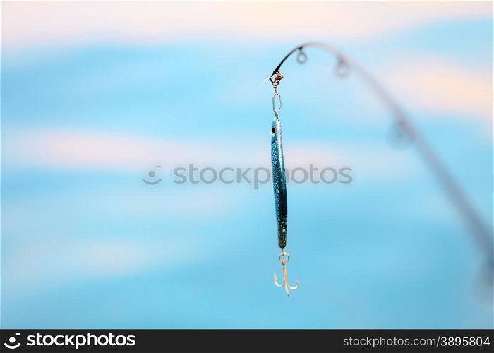 Sport and recreation. Fishing bait - rod with wobbler against the blue sea water surface