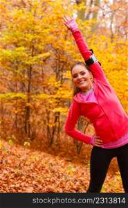 Sport and recreation. Fit slim sporty girl stretching warming up outdoor in autumnal park forest. Woman exercising on fresh air.. Dynamic girl stretching in forest.