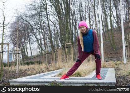 Sport and recreation. Fit slim sporty teen girl stretching warming up outdoor in park. Woman exercising on fresh air.. Sporty girl stretching outdoor in park.