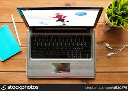 sport and technology concept - close up of laptop computer with fitness application on screen on wooden table. close up of laptop computer with fitness app
