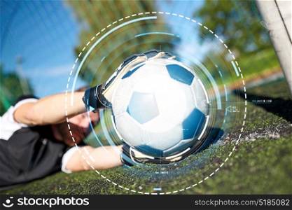 sport and technology - soccer player or goalkeeper lying with ball at football goal on field. goalkeeper with ball at football goal on field